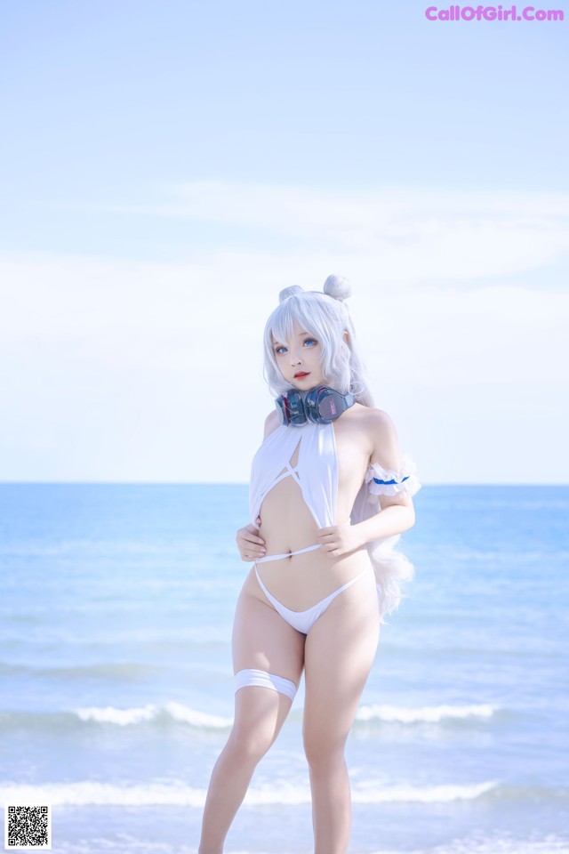 A woman in a white bikini standing on the beach.