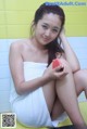 A woman sitting on the floor holding a slice of watermelon.