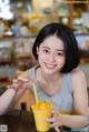 A woman sitting at a table with a glass of orange juice.