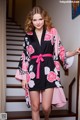 A woman wearing a black and pink floral robe.