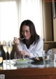 A woman sitting at a table with a plate of food and wine.