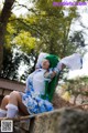 A woman with green hair sitting on a stone wall.