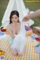 A woman sitting on a picnic blanket next to a teepee.