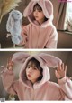 a woman wearing a pink bunny hoodie holding a stuffed animal