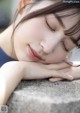 A young woman sleeping on a stone wall.