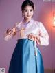 A woman in a blue and pink hanbok is posing for a picture.